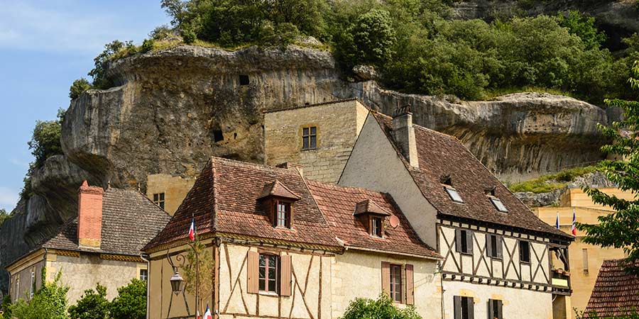 The quaint stone buildings of Les Eyzies sit next to the rugged cliffside. 